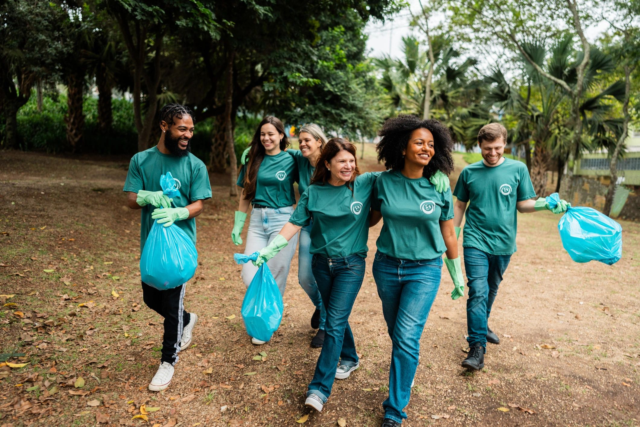 Group of volunteers walking holding garbage bag at public park