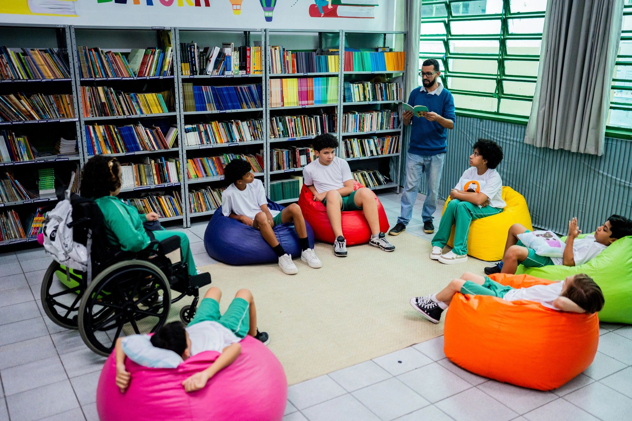 Teacher reading aloud to diverse group of students in school library